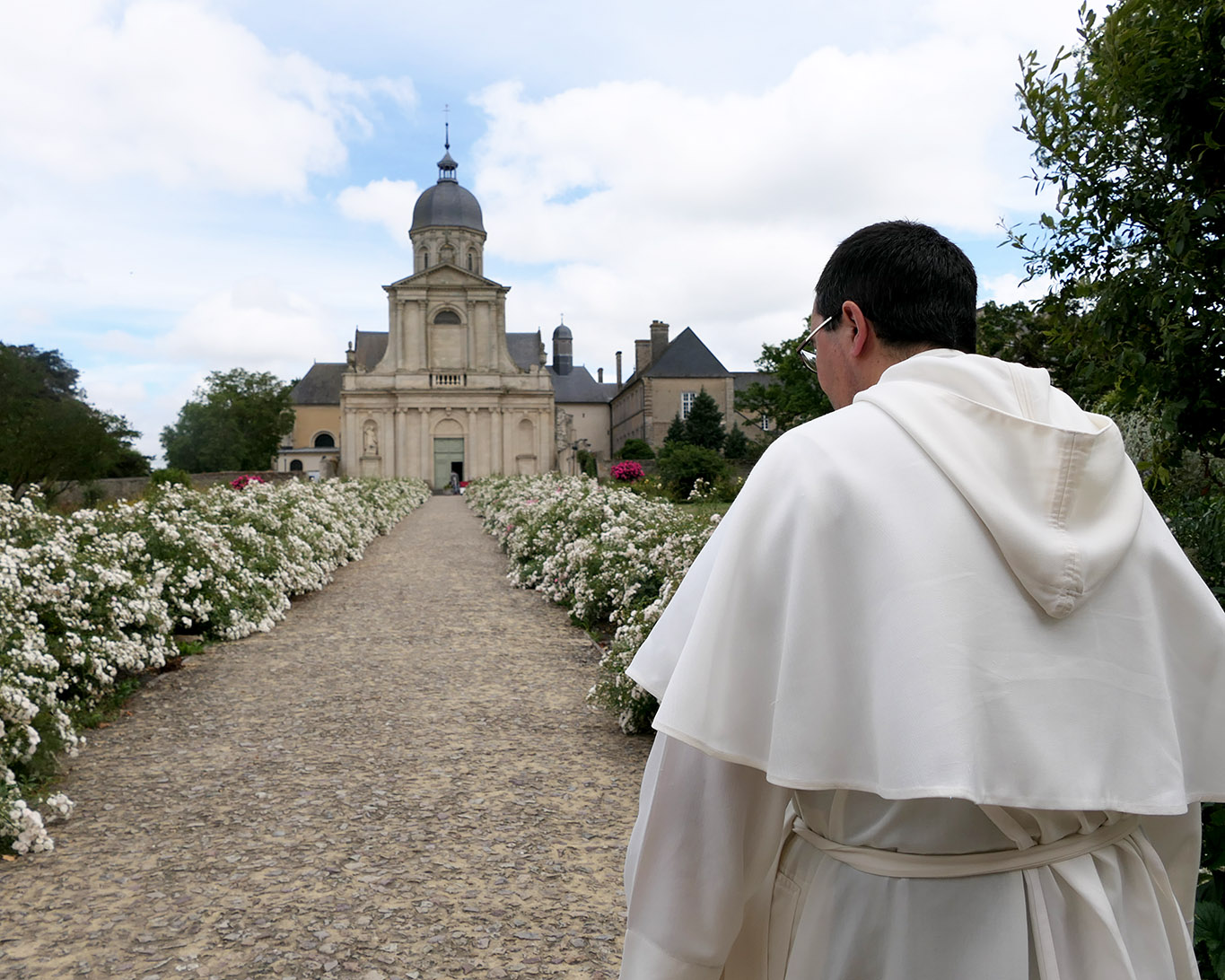 Ein Weg gesäumt mit weissen Rosen führt zur Abteikirche von Mondaye.